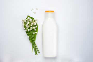 Cosmetic product and lily-of-the-valley flowers on white background. Top view. Flat lay.