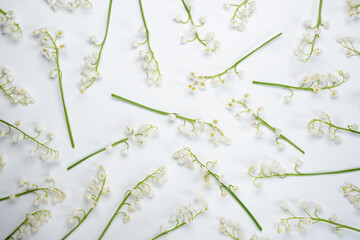 Seamless pattern of small white lilies of the valley on a white background. Top view, flat lay....