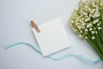 Flowers composition of lily of the valley flowers and blank square card for text on a white...