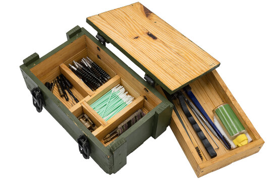 Interior of a military style wooden box with a firearm cleaning and maintenance kit on a white background. Brushes, grates, drumstick, oil, isopos, patches, hook, jag, cloth holder...