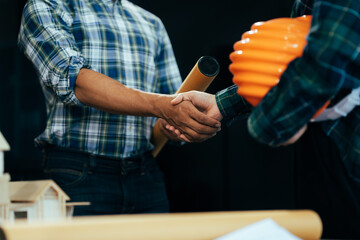 Construction workers, architects and engineers shake hands while working for teamwork and cooperation after completing an agreement in an office facility, successful cooperation concept.