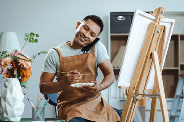 young male artist painting on canvas in the home studio, fine arts and creativity concept.