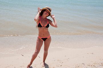 Summer vacation of woman in swimsuit and straw hat. Woman at sea beach. Suntan at summer beach. Beach vacation of young girl. Sea travel resort. Woman on summer vacation at beach. Copy space