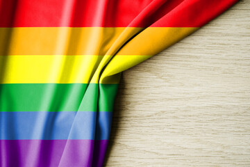 rainbow flag or LGBTQ, with a wooden background and copy space for text. 3d illustration.