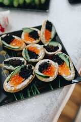 appetizers of red and black caviar on a black plate