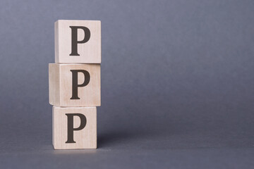 Stack of wooden blocks forming the acronym PPP, representing Purchasing Power Parity.