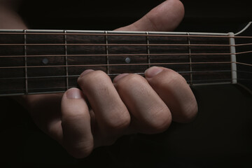 Playing an acoustic guitar. Close-up of the hand on the neck