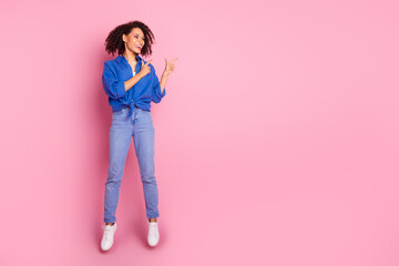 Photo of positive cheerful girl wear stylish blue clothes jump up introduce empty space isolated on pink color background