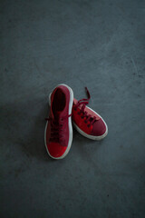 Red bright sneakers on a gray concrete floor - obrazy, fototapety, plakaty