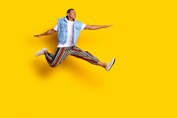 Full size photo of optimistic man dressed denim vest pants flying look at logo empty space isolated on vibrant yellow color background