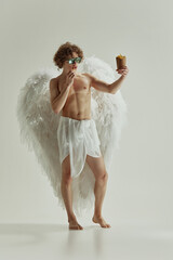 Classical and fast. Yong man with curls an large white wings, looks as angel, hold box of French...