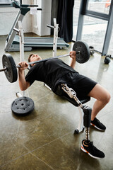 A man with a prosthetic leg is performing a bench press with a barbell in a gym setting.