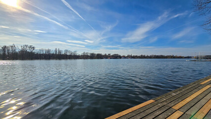 Wooden dock by water under sunny sky with clouds and distant horizon Maschsee Hanover