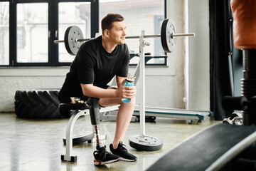 A man with a prosthetic leg, holding a water bottle, sits peacefully on a bench, taking a moment of...