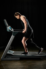 A man with a prosthetic leg runs on a treadmill in a gym, showcasing determination and strength in...