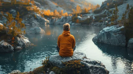 Gartenposter Person Sitting on Rock Looking at Lake © olegganko