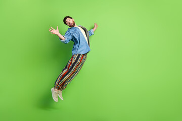 Full length photo of shocked good mood guy dressed jeans shirt jumping high empty space isolated...