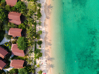 Aerial top down view of a beach with turquoise clear water trees bungalows and huts in Koh Phangan...