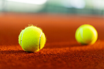new tennis balls on orange clay court with light from right