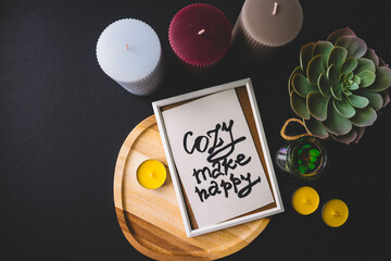 Candles, wooden board, photo frame and cactus on a black background. Copy space