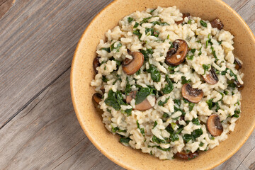 Homemade lemon risotto with spinach and portobello mushroom. Rustic wooden background with space for text. Healthy vegan eating concpt.