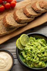 Homemade sourdough bread slices on an olive wood kitchen board, chunky guacamole decorated with...