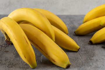 Two bunches of bananas lying on a gray surface. 