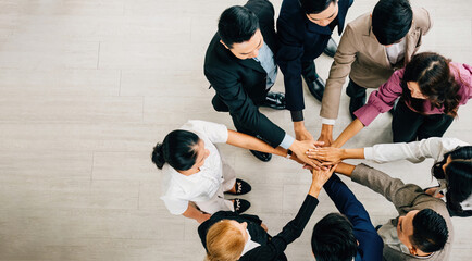 Aerial perspective of four diverse professionals in a circle hands stacked in unity. This image...