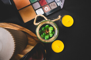 Candles, wooden board, shadow, cactus, makeup brushes and sunglasses on a black background. Copy...