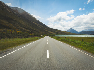 Open road with beautiful skies, lakes and mountains in distance