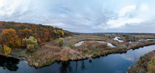 Fototapeta premium Aerial autumnal river valley panorama with autumn forest and scenic clouds in Ukraine
