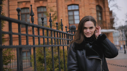 Happy brunette girl posing in black jacket in autumn in the city.