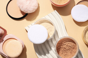 Bottles of face powder, different shades, on a pastel background.