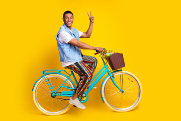 Full size photo of cheerful nice man dressed denim vest riding cycle to empty space show v-sign...