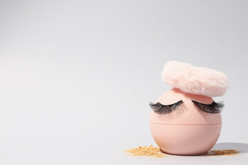 Face powder, with a puff for application, on a light background.