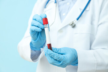 Doctor with test tube with donor blood in hands on blue background
