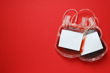 Bags with donor blood on red background, space for text