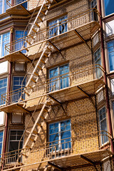 Typical fire escape ladders and platforms on the front facade of city building in San Francisco, California (USA) on a sunny day. Safe escape route in case of fire, mandatory for residential buildings