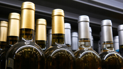 Close-up of many silver and golden wine bottles on a store shelf