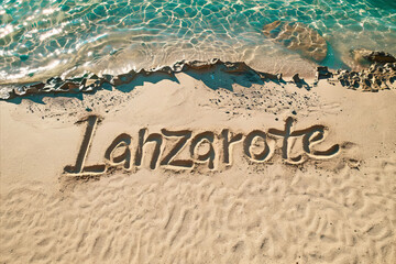 Fototapeta premium Lanzarote, Spain written in the sand on a beach. Spanish tourism and vacation background