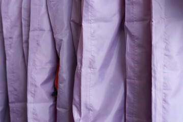 Cropped view of purple clothing covers on hanger in row. Background with copy space for your design.