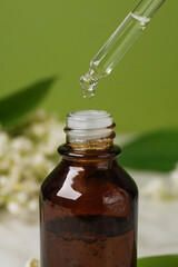 Lily of the valley essential oil in a small bottle. Side view. Selective focus. Nature.      