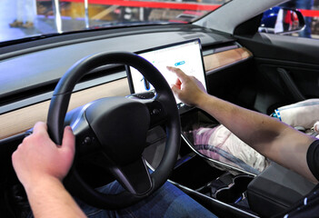 Male driver manipulating a touch screen monitor in cabin of an electric car