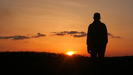 Man silhouette with outstretched arms against a vibrant sunset afterglow