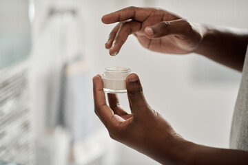 African man taking cream out of a jar with his finger
