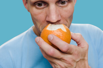 Young man with long-term effect of anosmia trying to sense smell of fresh orange. Anosmia...