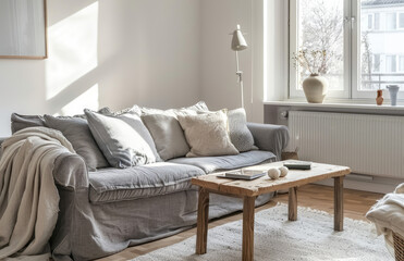 Scandinavian style living room interior with grey sofas, a wooden coffee table and shelf against a white wall near a window