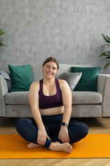 Sporty plus size woman in sportswear working out at home. Sports, activity and weight loss concept. Young plus size woman in leggings exercising on the mat, full body