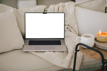 Laptop and white mug with tea on a sofa. Workspace in a modern room. - obrazy, fototapety, plakaty