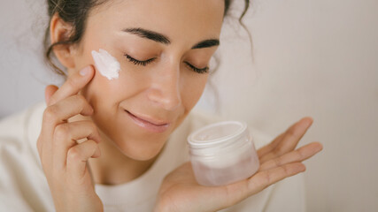 Young woman 30 years old applying face cream on her skin.